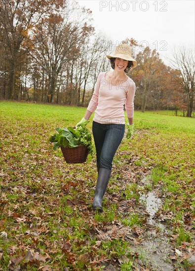 Woman walking with basket of vegetables.