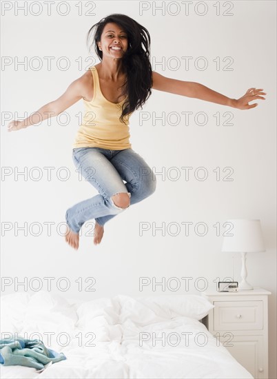 Woman jumping on bed