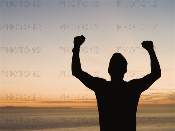 Silhouette of man raising arms