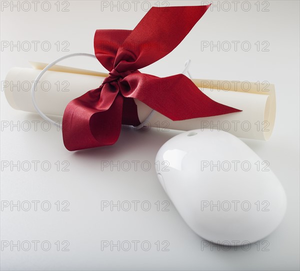 Red ribbon on diploma beside computer mouse