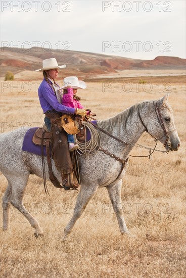 Mother and daughter riding horse.