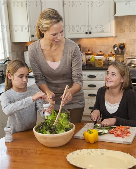 Mother and daughters making salad.