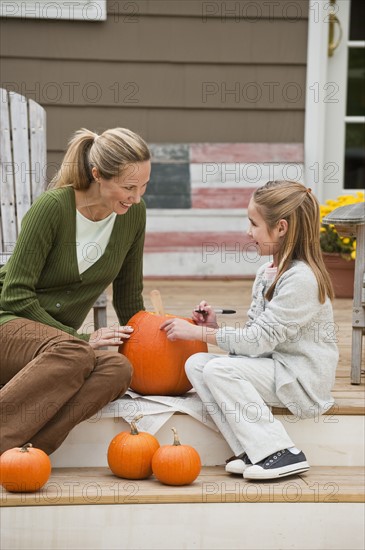 Mother and daughter carving pumpkin.