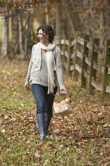 Woman walking with basket of apples.