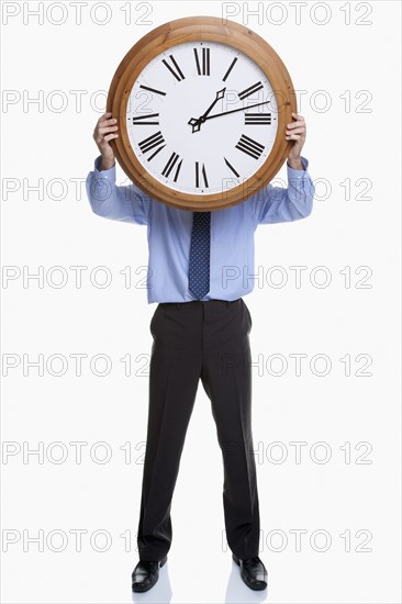 Man holding clock in front of face
