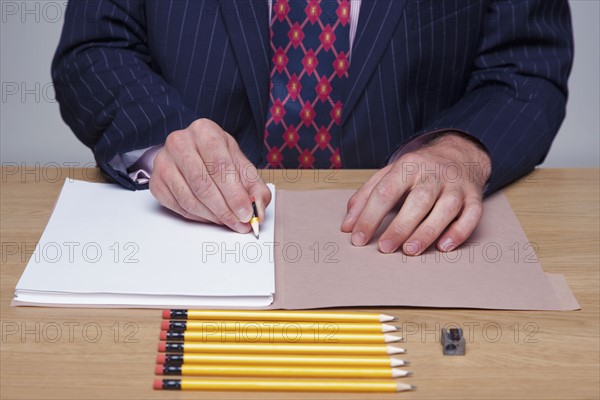 Man writing on paper with tiny pencil