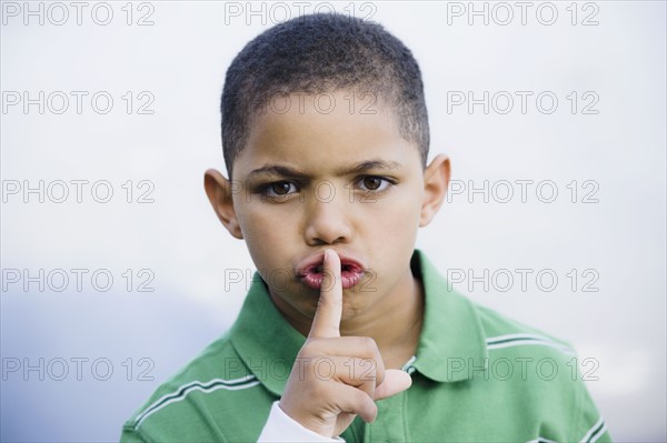 Boy with finger in front of mouth