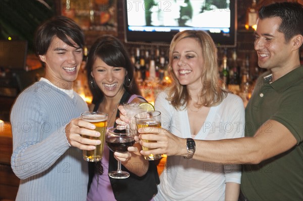 Friends toasting at bar.