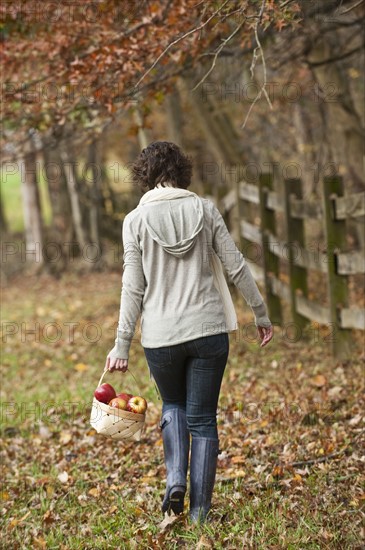 Woman walking with basket of apples.