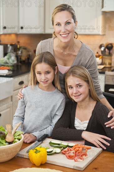 Mother and daughters making salad.