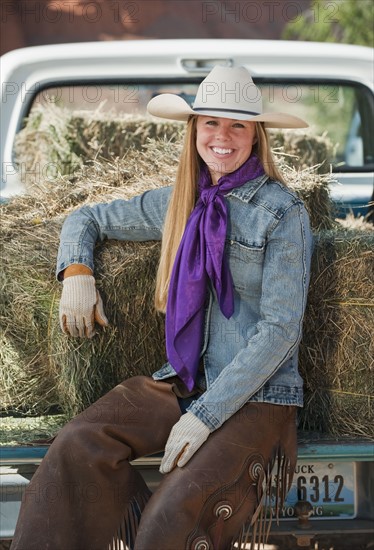 Cowgirl sitting on back of truck.