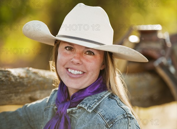 Cowgirl beside fence.