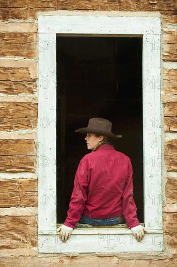 Cowgirl sitting on window ledge.