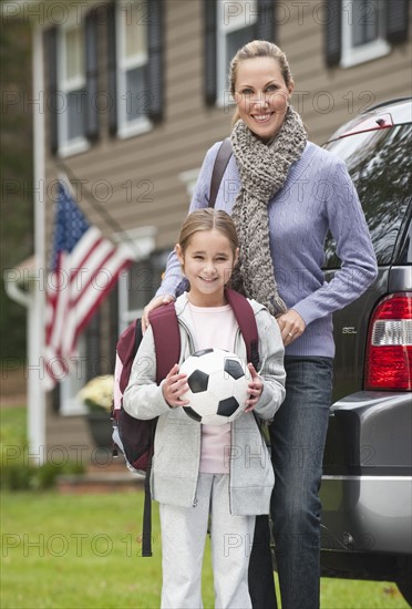 Mother and daughter holding soccer ball.