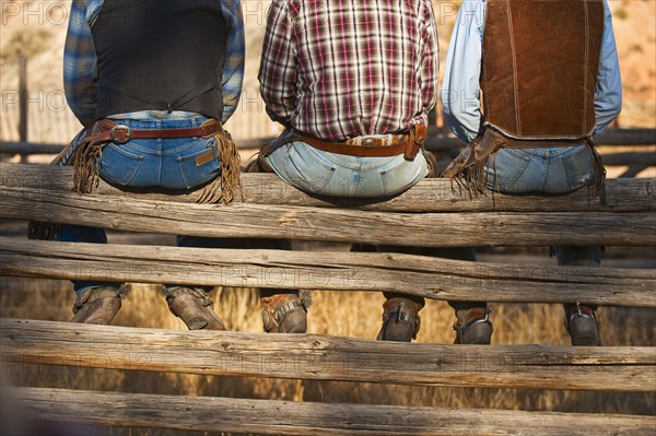 Cowboys sitting on fence.