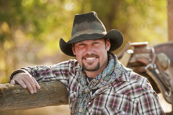 Cowboy leaning on fence.