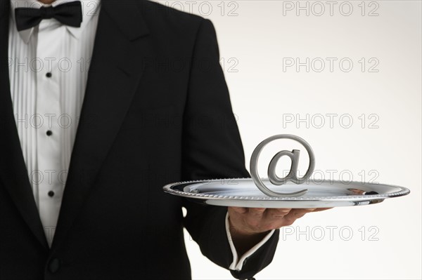 Butler holding at symbol on silver tray.