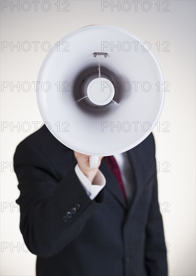 Businessman speaking into bullhorn.