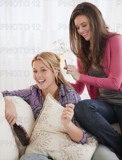 Woman brushing friends hair. Photographer: Jamie Grill