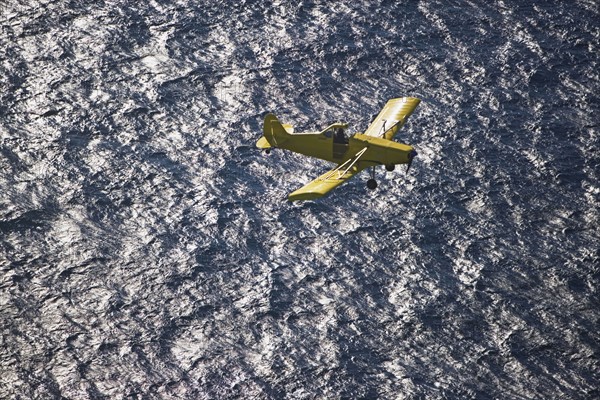 Small airplane ascending over water. Photographer: fotog