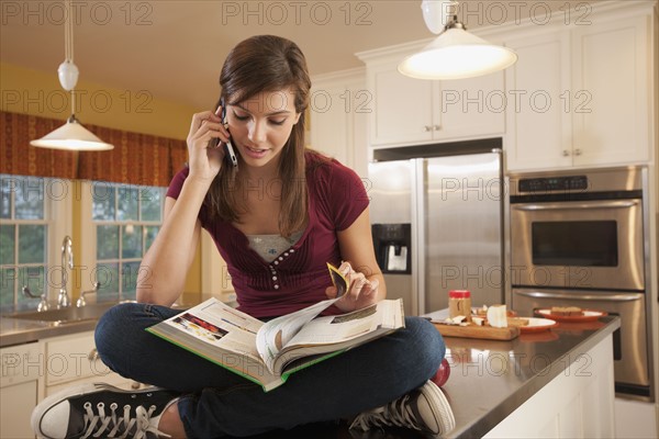 Girl sitting on kitchen counter. Photographer: mark edward atkinson