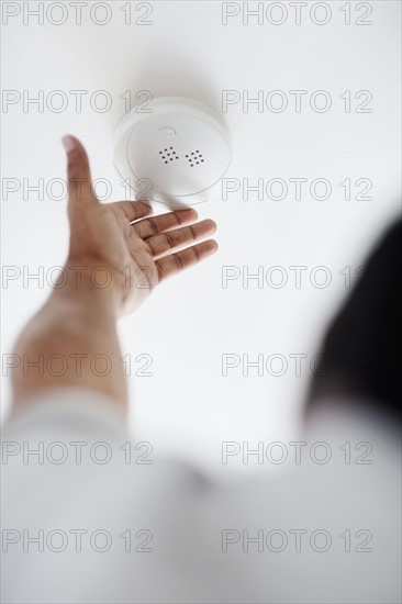 Testing battery in smoke detector. Photographer: momentimages