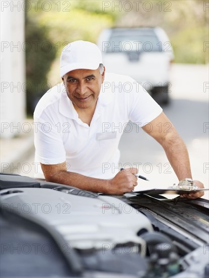 Man looking at car's engine. Photographer: momentimages