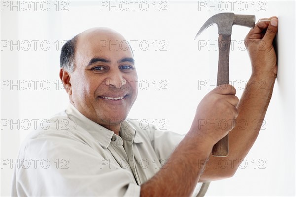 Man hammering nail into wall. Photographer: momentimages