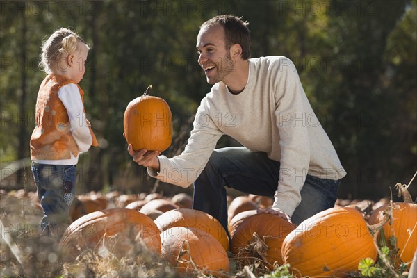 Father and daughter in pumpkin patch. Photographer: Mike Kemp