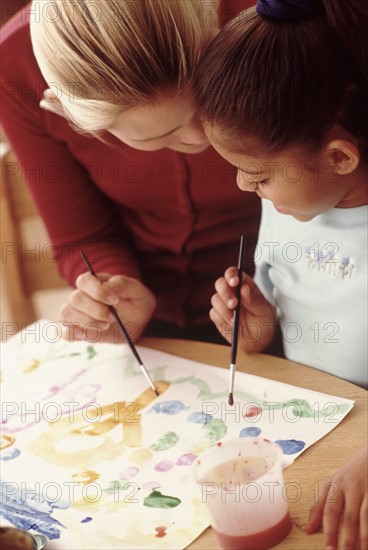 Student painting with teacher. Photographer: Rob Lewine