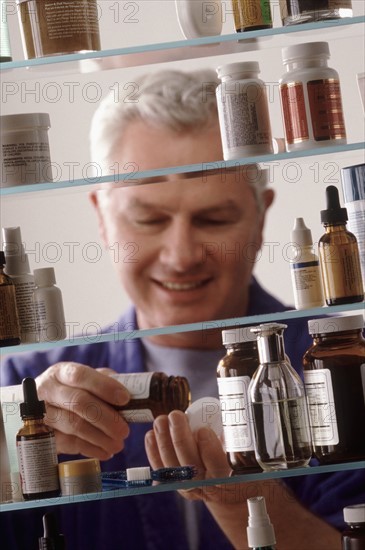 Man in front of medicine cabinet. Photographer: Rob Lewine