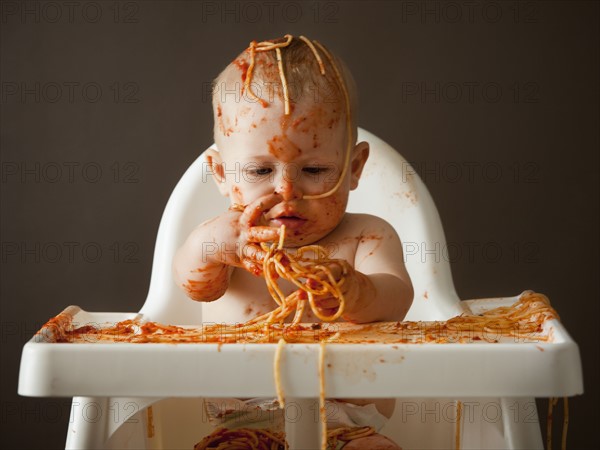 Baby covered in spaghetti. Photographer: Mike Kemp