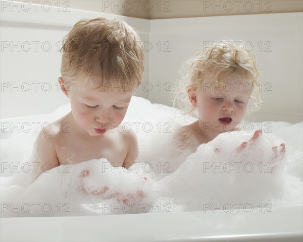 Children playing with bubbles in the bath tub. Photographer: Mike Kemp