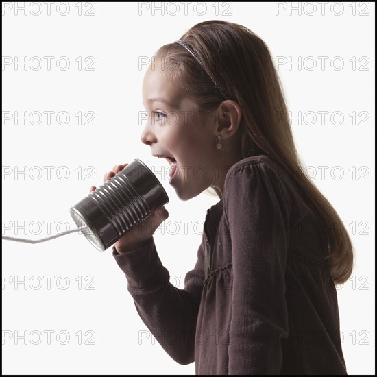 Girl playing with tin can phone. Photographer: Mike Kemp