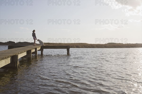 Woman and dog on pier. Photographer: Chris Hackett