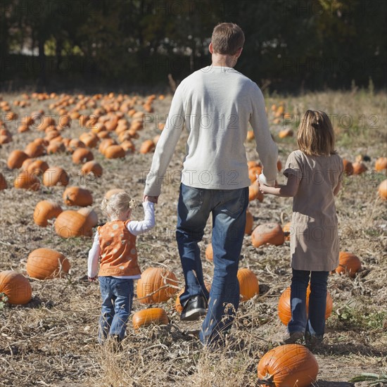 Father and daughters in pumpkin patch. Photographer: Mike Kemp