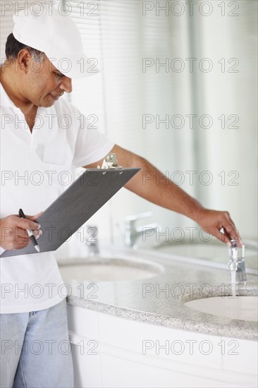 Plumber testing sink. Photographer: momentimages