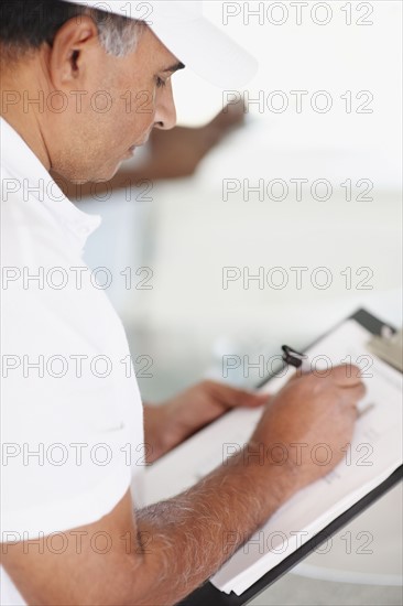 Repair person writing on clipboard. Photographer: momentimages