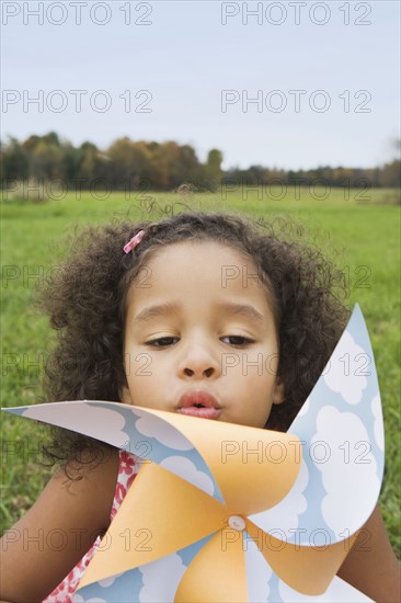 Young girl blowing toy windmill. Photographer: Pauline St.Denis