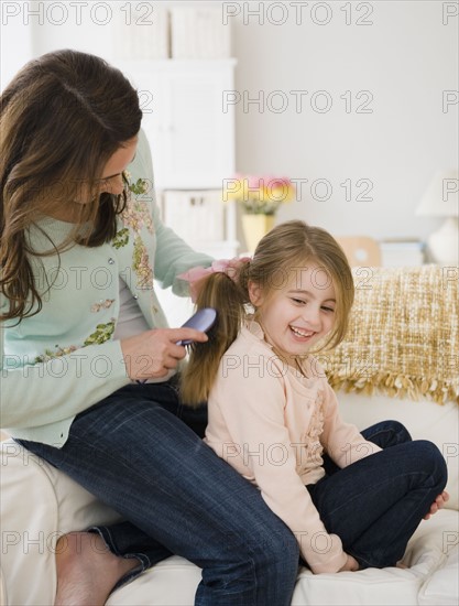 Mother brushing daughter's hair. Photographer: Jamie Grill