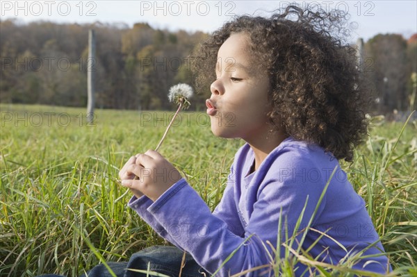 Young girl blowing dandelion. Photographer: Pauline St.Denis