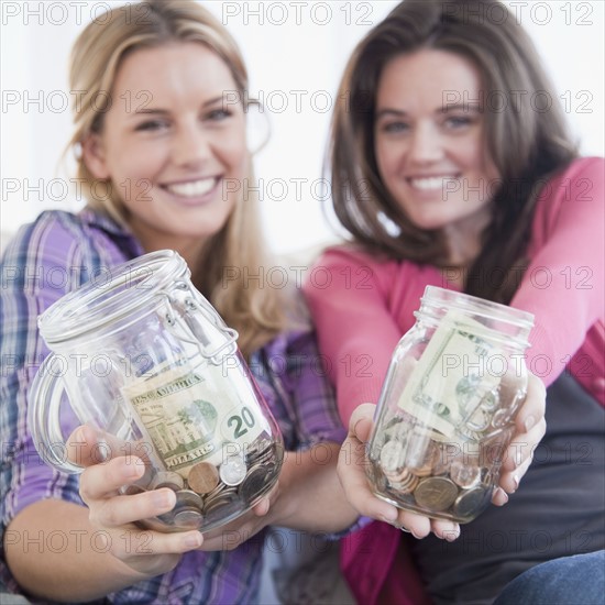 Woman holding jars of money. Photographer: Jamie Grill