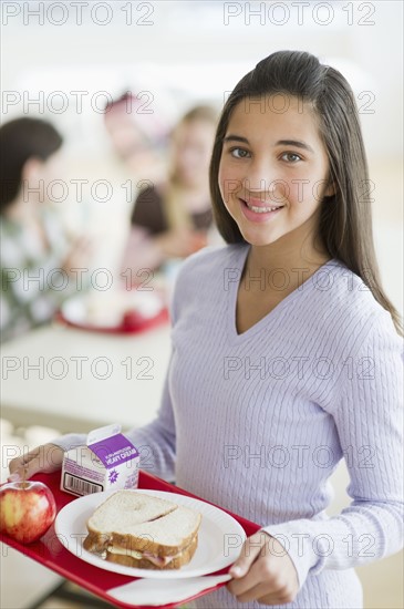 Girl holding tray of cafeteria food.
