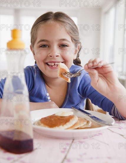 Young girl eating pancakes. Photographer: Jamie Grill