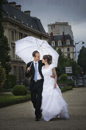 Bride and groom walking in the rain. Photographer: Mike Kemp