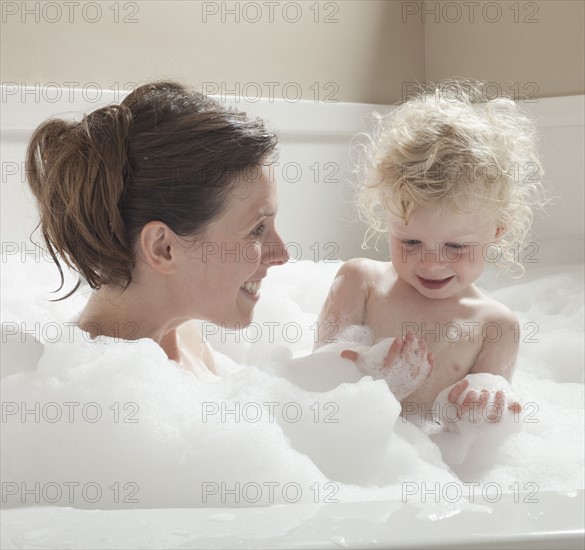 Mother and child having bubble bath. Photographer: Mike Kemp