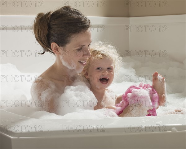 Mother and child having bubble bath. Photographer: Mike Kemp