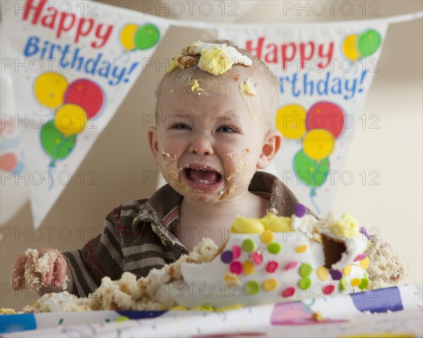 Baby covered in birthday cake. Photographer: Mike Kemp