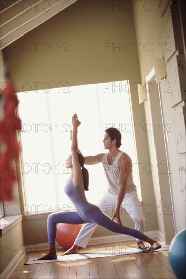 Yoga instructor helping student. Photographer: Rob Lewine