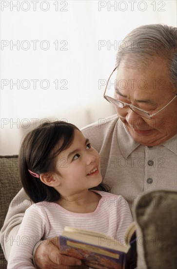 Grandfather reading to granddaughter. Photographer: Rob Lewine